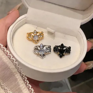 Close-up of gothic fleur-de-lis rings in gold, silver and black inside a white jewelry box