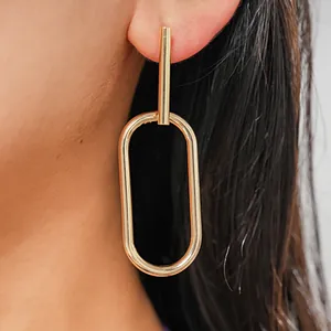 Close-up of minimalist gold oval geometric earring worn on a model's ear.