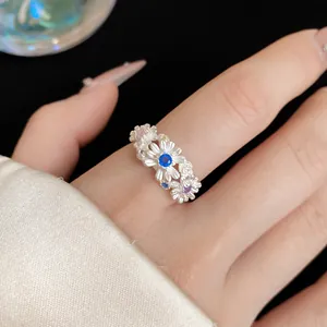 Detailed view of an elegant floral daisy ring with colorful crystals on a finger
