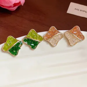 Detail macro view of four 14K gold-plated geometric stud earrings with crushed glass inlay