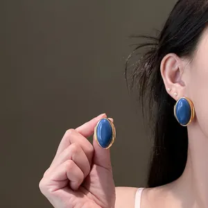 Close-up view of vintage oval stud earrings featuring a deep blue stone and gold-toned bezel