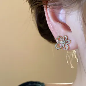 Close-up detail of 18K gold-plated flower stud earrings with sparkling zircon on ear