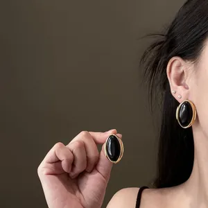 Close-up of vintage-style oval earrings featuring black cabochon and gold trim