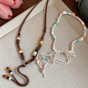 Close-up detail of bohemian braided waist chains featuring natural shells and wooden beads