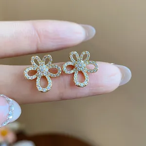 Close-up view of elegant flower stud earrings with gold plating and pavé set zircons
