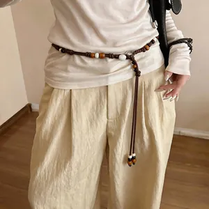 Bohemian woven waist chain featuring wooden beads and shell accents worn on model