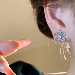 Elegant zircon flower stud earring with 18k gold plating shown on woman's model ear