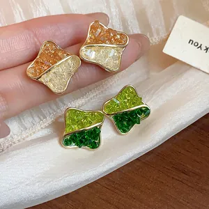 Detail of two-tone geometric stud earrings with 14K gold plating and crushed glass inlay