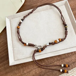 Detail view of bohemian braided waist chain with colorful wooden beads on a white tray.