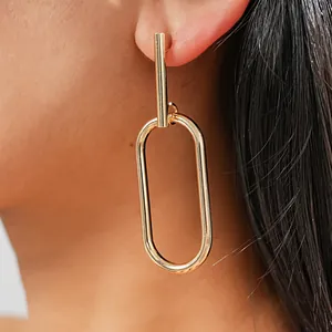 Detailed view of elegant gold-toned geometric oval loop drop earrings worn by a model
