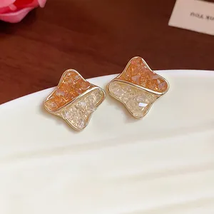 Close-up macro detail of geometric stud earrings with orange and white crushed glass stones
