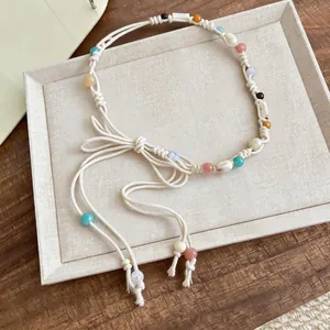 Close-up detail of a Bohemian braided rope waist chain with colorful beads and shells.