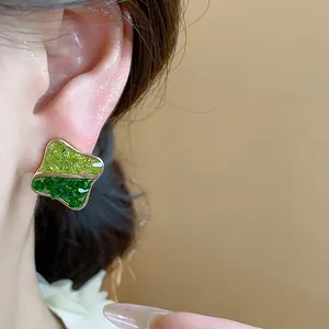 Detailed macro shot of a two-tone green crushed glass geometric earring on model ear.