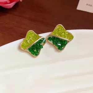 Detail of geometric stud earrings with green crushed glass in gold plating