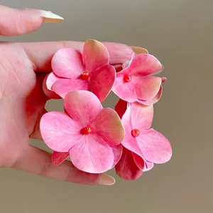 Close-up of sweet pink flower earrings with delicate petal design and red bead centers.