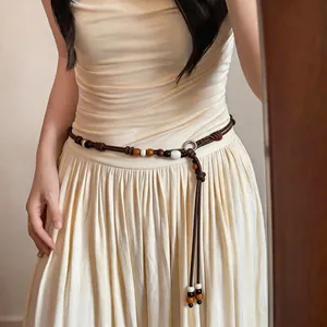 Close-up of Bohemian wooden bead braided waist chain worn on a cream summer dress.