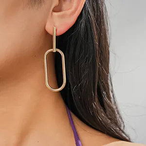 Close-up of minimalist gold-tone geometric oval earrings style worn by a model