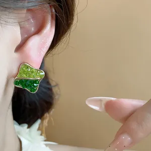 Close-up of geometric gold-plated earrings with dual-tone green glass