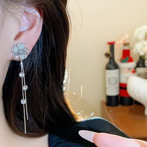 Close-up of elegant silver needle zircon flower tassel earrings on an Asian model