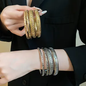 Detailed close-up view of stacked geometric metal bangles in gold and silver finish.