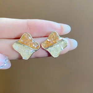 Macro view of geometric two-tone glass stud earrings with 14K gold plating