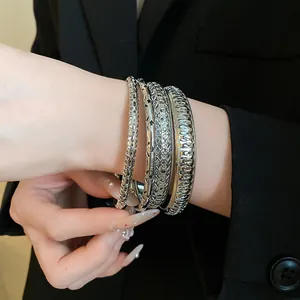Close-up of a stylish four-piece silver metallic geometric bracelet set worn on a wrist