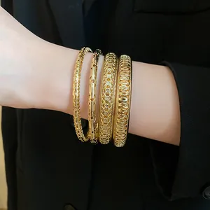 Close-up of four-piece gold geometric bracelet set worn on wrist with black blazer