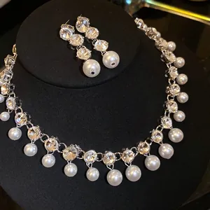 Elegant jewelry set with rhinestone and pearl pendant necklace and earrings on display