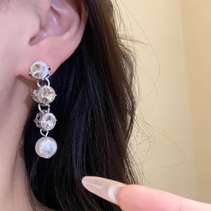 Elegant close-up of a vintage style rhinestone and pearl drop earring worn on a model's ear