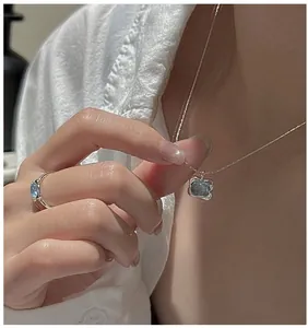 Close-up of jelly blue square zircon pendant necklace and matching ring on model.