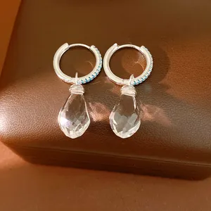 Close-up detail view of teardrop glass earrings with blue zircon-encrusted silver hoops