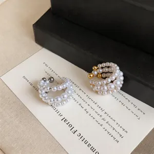 Dettaglio di orecchini a clip in perle multistrato stile francese su carta.