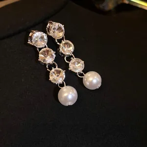 Elegant vintage rhinestone and pearl dangle earrings presented on black velvet background.