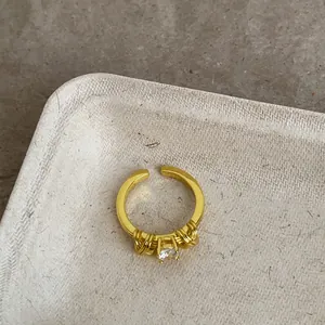 Dettaglio di un anello vintage dorato con pietra di zircone e fascia intrecciata