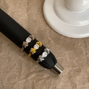 Primo piano dettagliato che mostra l'intricato design a incrocio di anelli vintage con zirconi.
