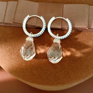 Detailed view of silver hoop earrings with clear teardrop glass pendants and blue accents.