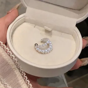 Dettaglio macro di un elegante earcuff di perle bianche a doppio strato in una scatola per gioielli