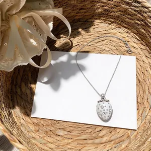 Collana con ciondolo a forma di fragola in resina e strass in un cesto intrecciato.