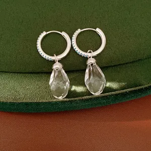 Detailed view of silver hoop earrings with clear glass water drop pendants and blue zircon