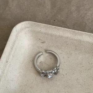 Dettaglio di un anello aperto vintage in argento con zircone scintillante e design incrociato