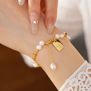Dettaglio del bracciale in perle placcato oro 18K con ciondolo Good Luck inciso.