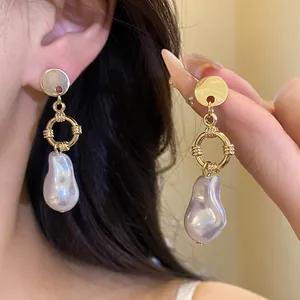 Primo piano dettagliato di eleganti orecchini pendenti in oro con perle barocche naturali
