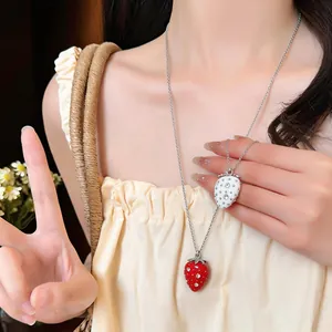 Vista dettagliata di una dolce collana a fragola in resina con strass su una modella