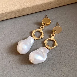 Eleganti orecchini pendenti d'oro con perle barocche su sfondo minimalista