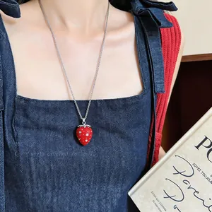 Primo piano di una collana con ciondolo a fragola in resina rossa e semi di strass.