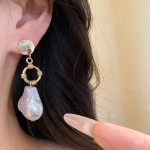 Primo piano di elegante orecchino a cerchio in oro e perla barocca indossato
