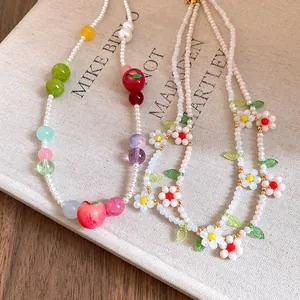 Close-up of pearl and resin apple beaded necklace with colorful floral details.