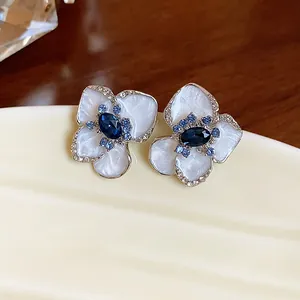 Detailed close-up of vintage enamel flower stud earrings with blue rhinestones
