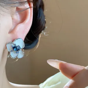 Close-up detail of vintage enamel flower stud earring with blue gemstone center