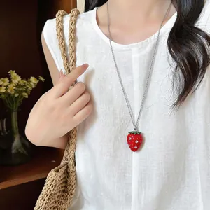 Vista ravvicinata di una collana a fragola rossa in resina con cristalli su lino